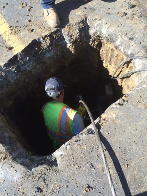 sewer line being replaced using trenchless method by plumber in pit